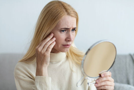 women holding a pocket mirror looking at her wrinkles