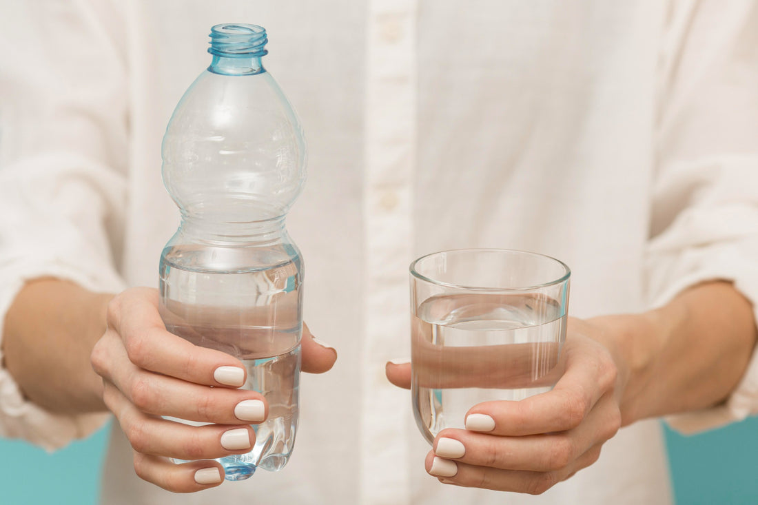 A person holding a water bottle and a glass of water